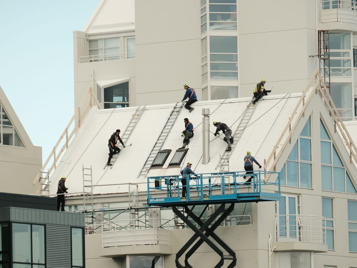 Construction workers repairing a modern roof in Reykjavík, highlighting teamwork and safety.